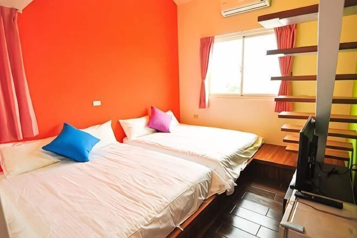 A room with two beds, a TV, a window with curtains, and a shelf with items.