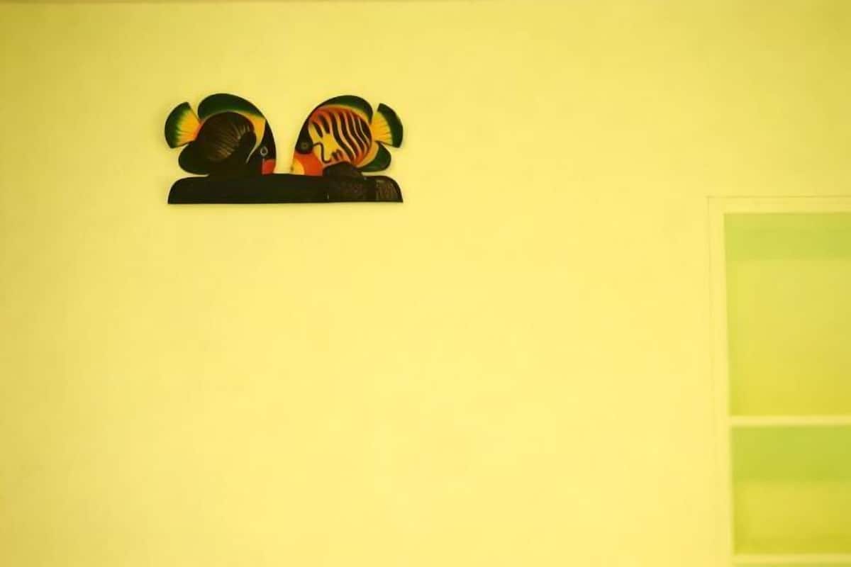 A yellow wall with a black and orange abstract art piece.