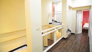 A hallway with a glass railing, a staircase, and a bed with red curtains. - Peng Hu Dream (Penghu)