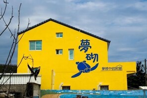 A yellow building with a turtle logo and Japanese text. - Peng Hu Dream (Penghu)