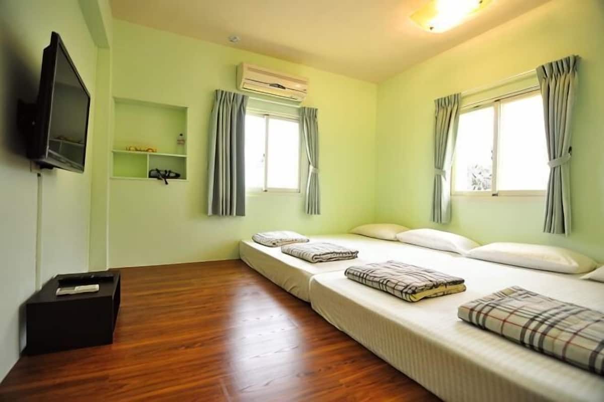 A room with two beds, a TV, and a window with curtains.
