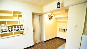 A hallway with a wooden floor, a door, a wall-mounted shelf with busts, and a decorative wall piece. - Peng Hu Dream (Penghu)