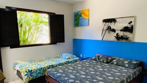 Een slaapkamer met een groot bed, een kleiner bed en een raam met zonwering.