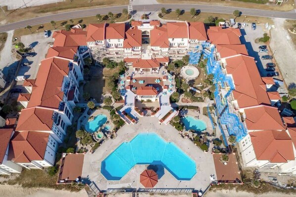 Vista aérea de un hotel con varias edificaciones, una piscina central y servicios aledaños.