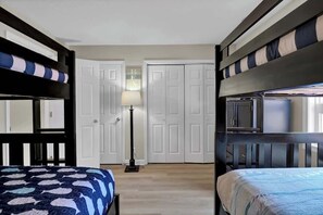 Un dormitorio con literas, una lámpara de noche y puertas blancas al fondo.