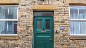 A green door with a small window above it, set in a brick wall.