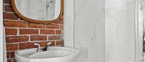 A bathroom with a white sink, a mirror with a wooden frame, and a glass shower enclosure.