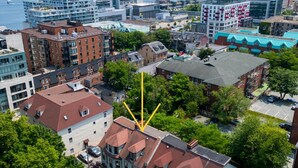 Un paisaje urbano con una mezcla de edificios modernos y tradicionales, vista al agua y una grúa amarilla destacada.