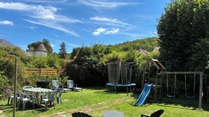 Ein Garten mit Trampolin, Rutsche und Gartenmöbeln.
