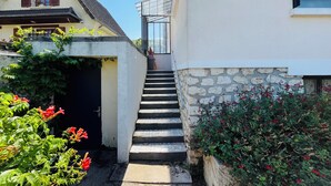 Ein schmaler Weg, der zu einer Treppe führt, an einer Seite eine Steinmauer und am anderen ein Hauseingang.