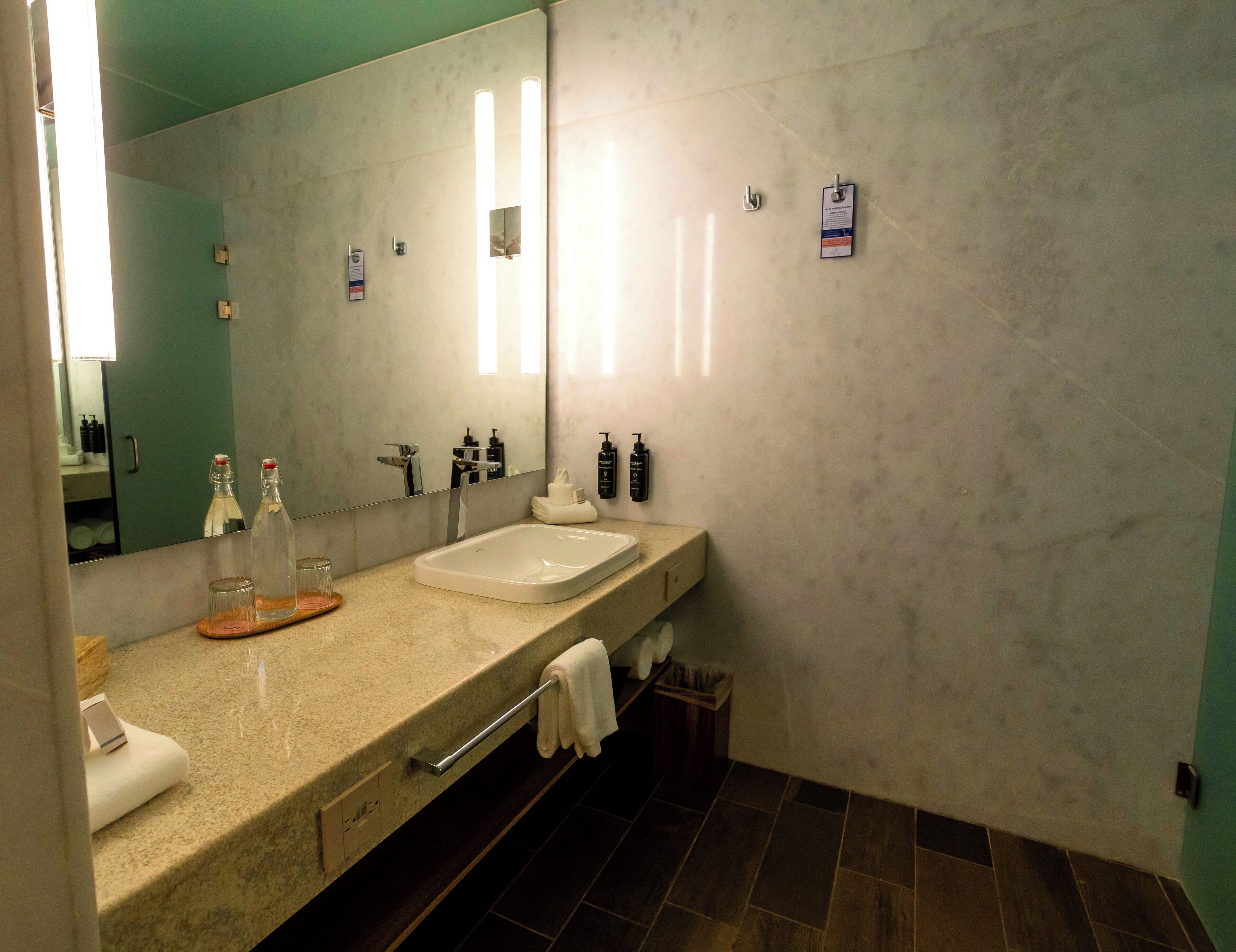 A modern bathroom with a large mirror, a sink, and toiletries.
