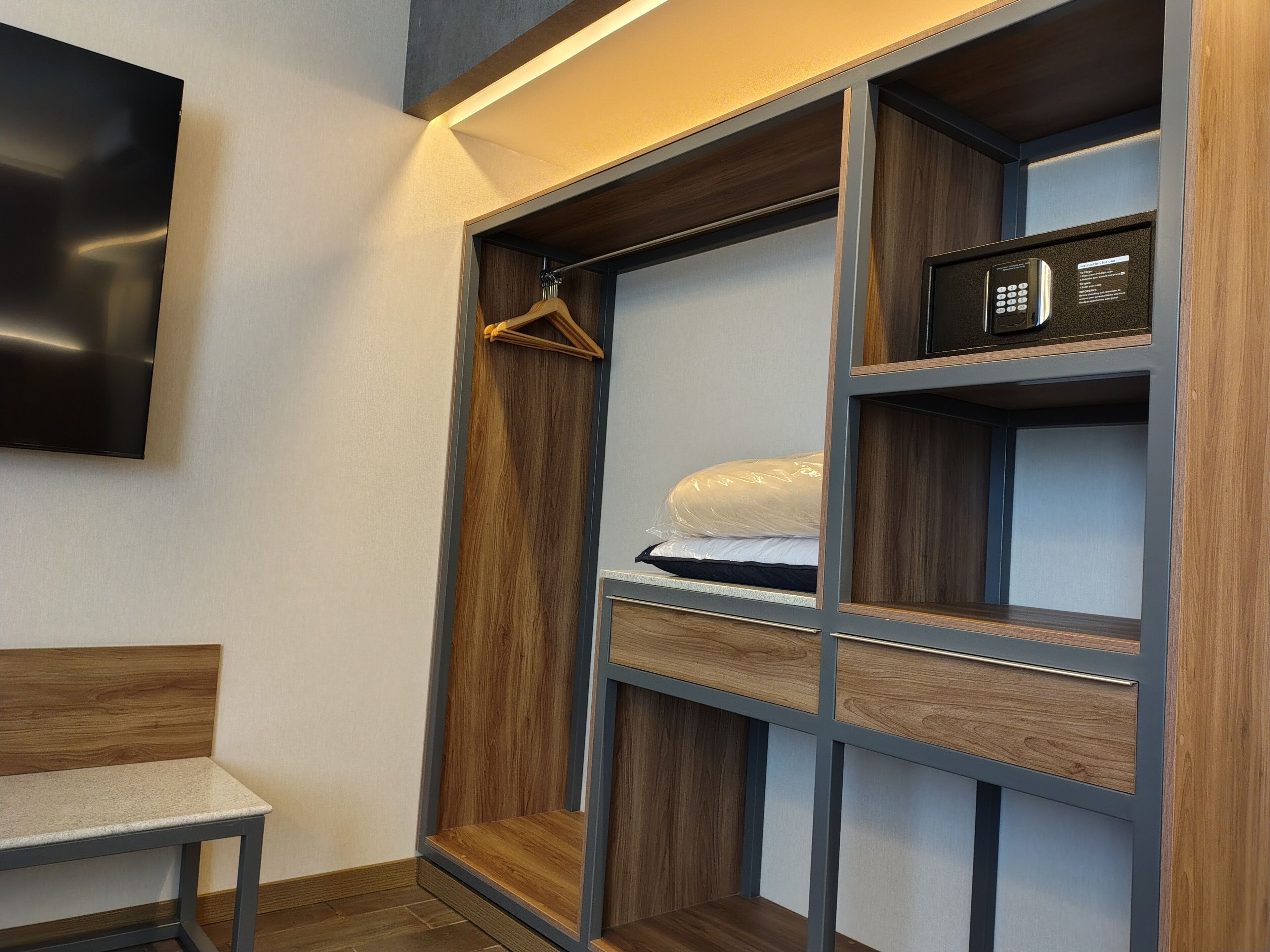 A modern room with a built-in wardrobe, a bed with a mattress and pillows, and a small table.