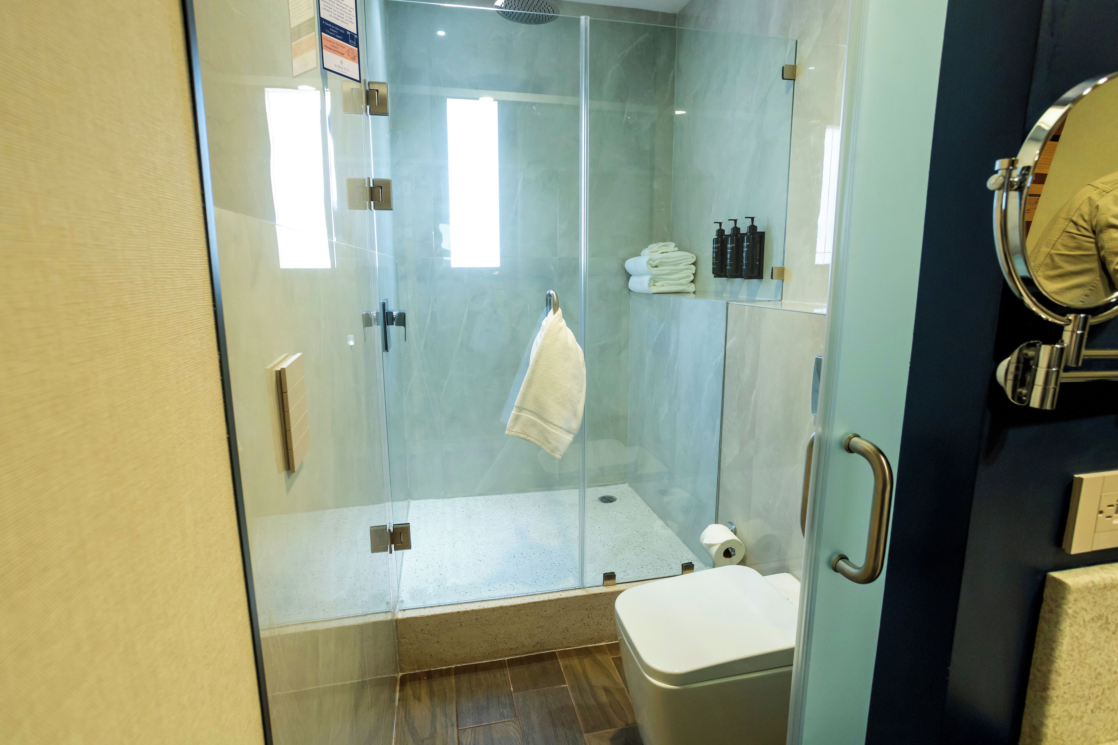A modern bathroom with a glass-enclosed shower, a toilet, and a sink.