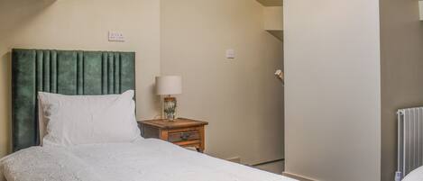 A bedroom with a large bed, a nightstand with a lamp, and a radiator.