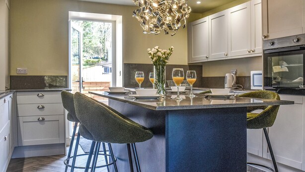 Une cuisine moderne dotée d’un îlot central, de tabourets de bar et d’un lustre décoratif.