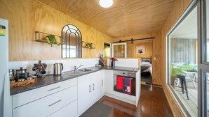 A modern kitchen with wooden walls, a built-in oven, and a large window. - Strathvale River Cottage - Winton Holiday Home (Winton)