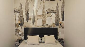 Un dormitorio con una cama, cabecera, pared con un mural temático de naturaleza y una lámpara colgante.