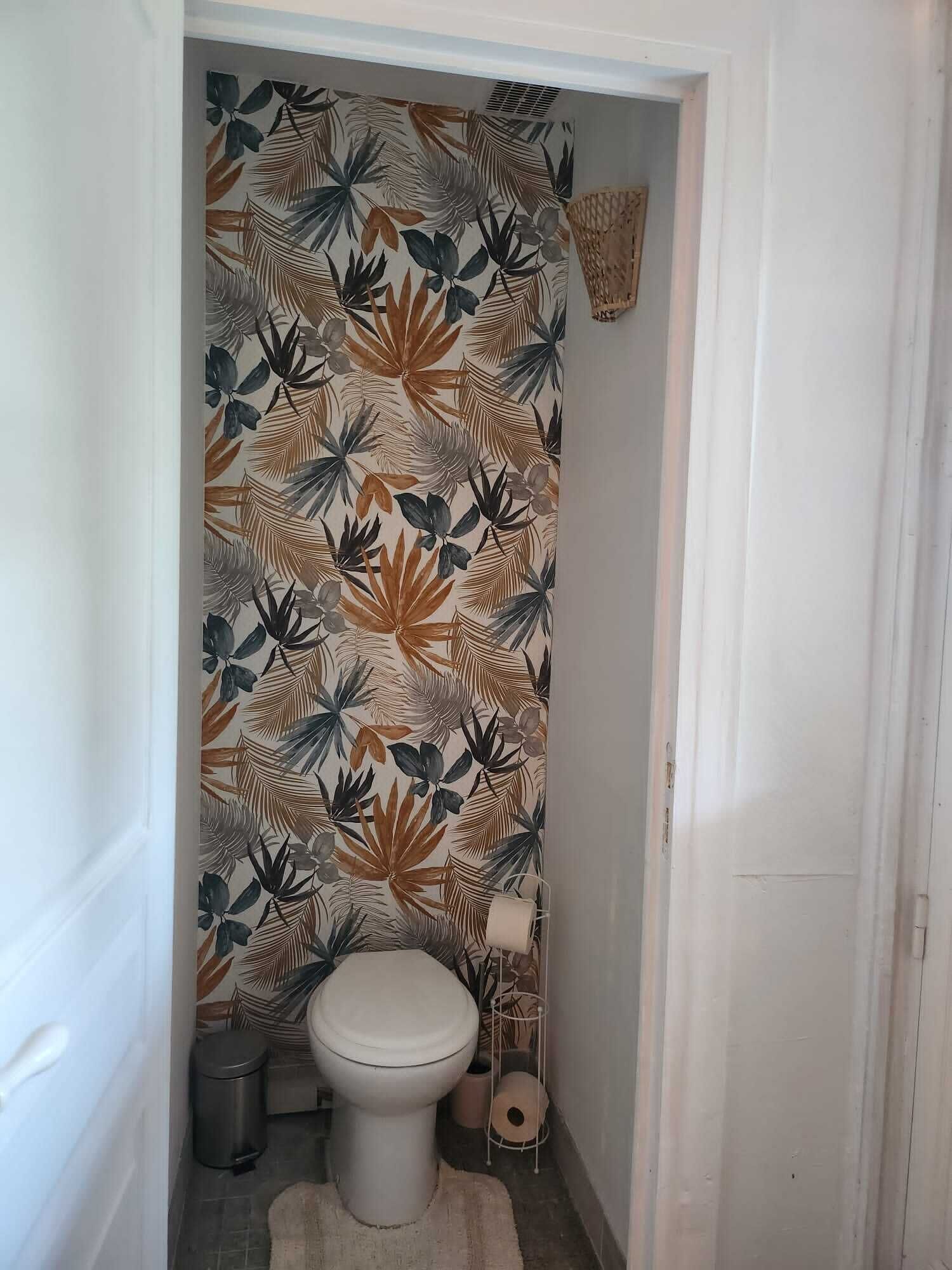 Un baño con un inodoro, un bote de basura y un dispensador de papel higiénico.