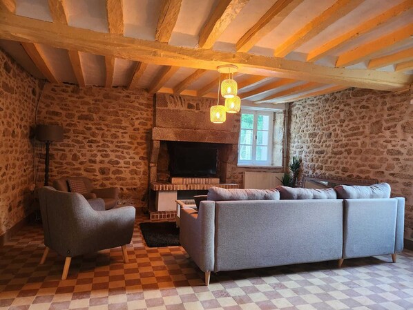 A cozy living room with a stone wall, a fireplace, a sofa, and a checkered floor.