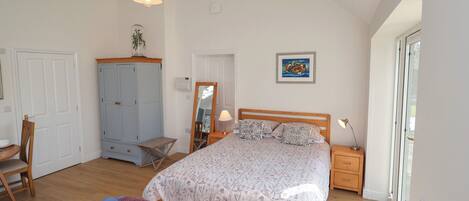 Una camera da letto con un letto, una sedia, un armadio, uno specchio, una lampada e una finestra.