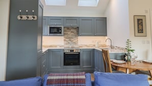 A compact kitchen with grey cabinets, a microwave, and an oven. There are two skylights providing natural light. - West End (Woodbridge)