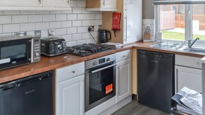A modern kitchen with white cabinets, a microwave, toaster, stove, oven, and dishwasher.