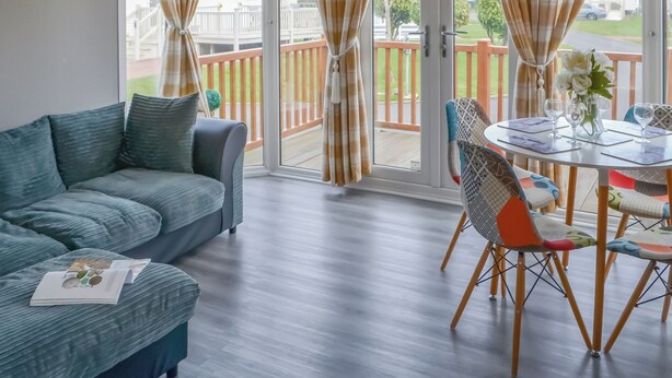 A living room with a sofa, a dining table with chairs, and a view of a deck and outdoor area.