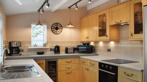 A modern kitchen with wooden cabinets, a built-in oven, a dishwasher, and a coffee maker.