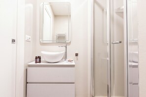 A modern bathroom with a white sink, mirror, and glass shower enclosure. - Elegant Flat in Ponte Milvio (Roma)