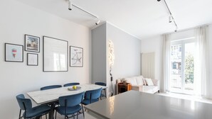 Een moderne woonkamer met een groot eiland, een eetgedeelte met blauwe stoelen en een bank.
