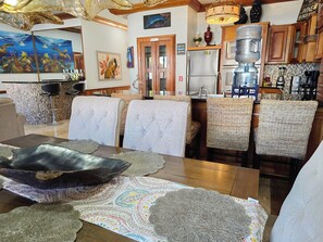 A dining area with a wooden table, woven chairs, and decorative placemats. - Oceans 23 (San Pedro)