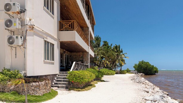 A beachfront hotel with multiple balconies, a sandy walkway, and a view of the ocean. - Oceans 23 (San Pedro)
