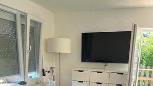 A modern living room with a blue sofa, a white coffee table, a TV on the wall, and a white storage unit. - Vacation home with Lilienstein view (Struppen)