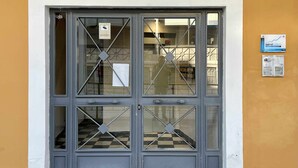 A building entrance with a large number '91' above the door, a glass window with a diamond pattern, and a sign on the wall to the right. - Zabella Central Market (Zaragoza)