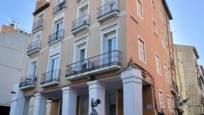 A multi-story building with balconies, a sign indicating a price of 30/15, and a person standing on the sidewalk. - Zabella Central Market (Zaragoza)
