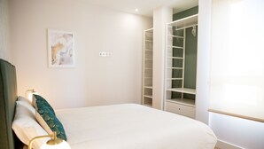 Ein Schlafzimmer mit Bett, Nachttischlampe und einem begehbaren Kleiderschrank mit Regalen.