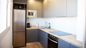 Eine kleine Küche mit einem Edelstahlkühlschrank, einer Mikrowelle, einem Spülbecken und einem Herd.