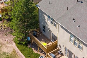 A two-story house with a deck, a satellite dish, and a small patio area.