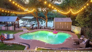Ein Garten mit Pool, Terrasse und Lichterketten.