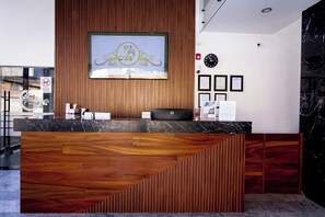 A hotel reception desk with a wooden finish and a large framed sign above it.