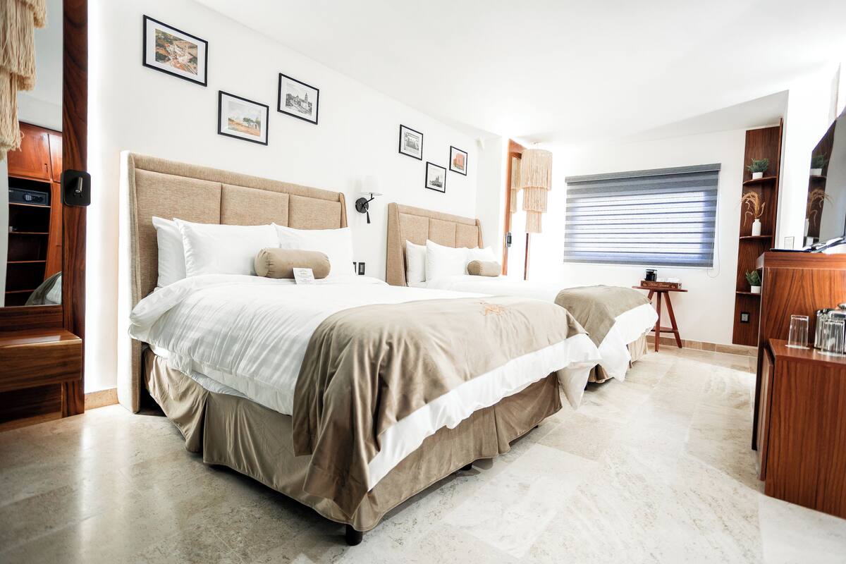 A spacious bedroom with a large bed, wooden furniture, and framed pictures on the wall.