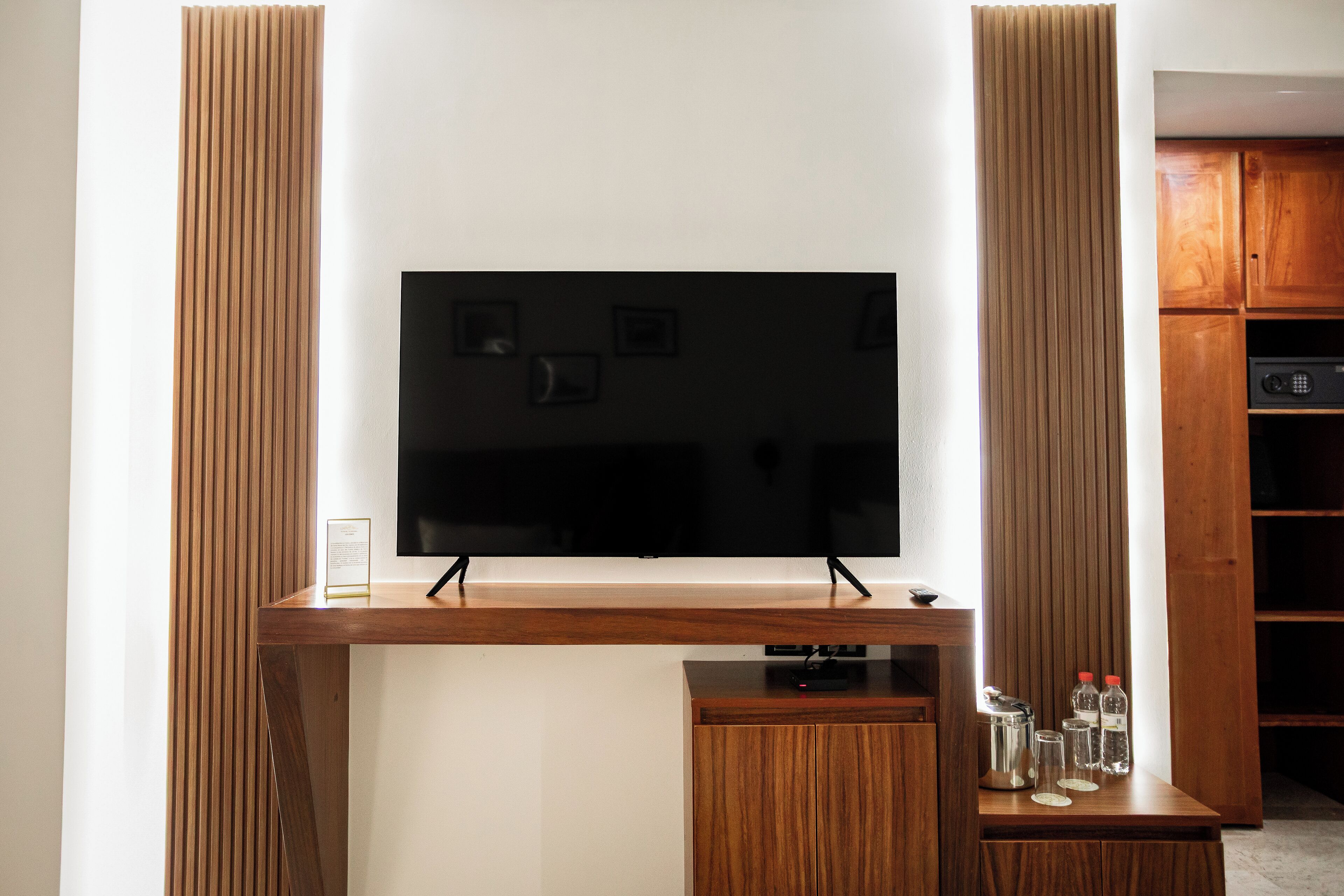 Una televisione a schermo piatto montata su un supporto in legno con un mobile sottostante.