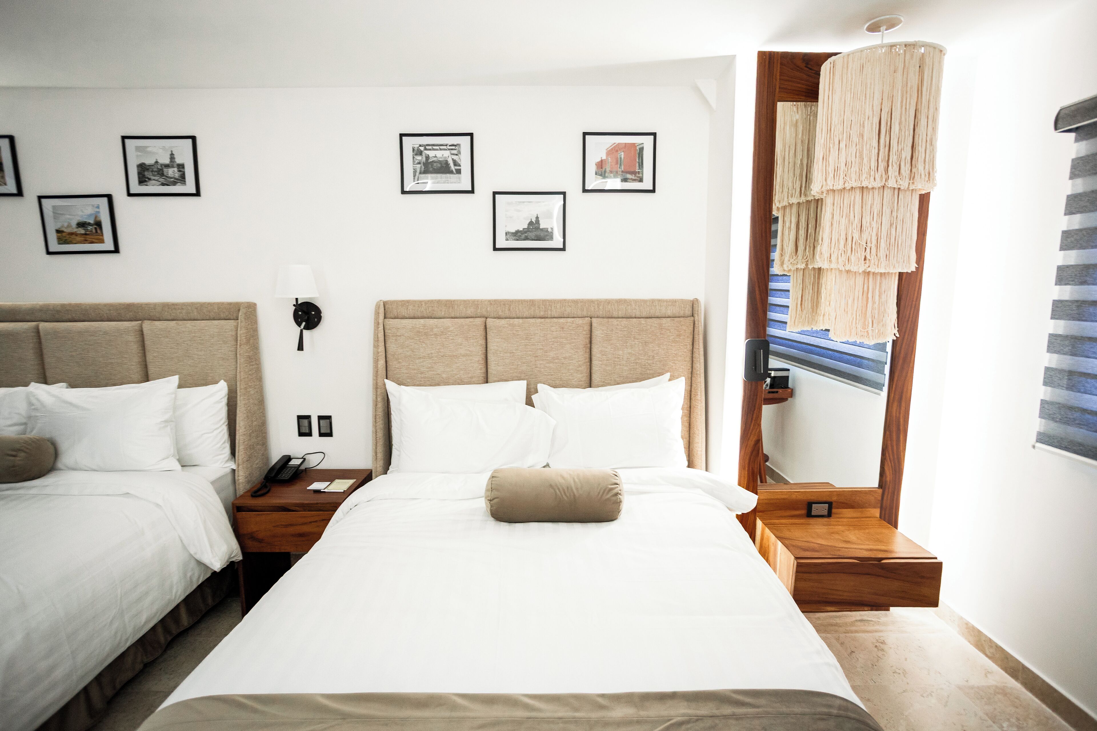 Une chambre d’hôtel avec deux lits, un grand miroir et des tableaux encadrés accrochés au mur.