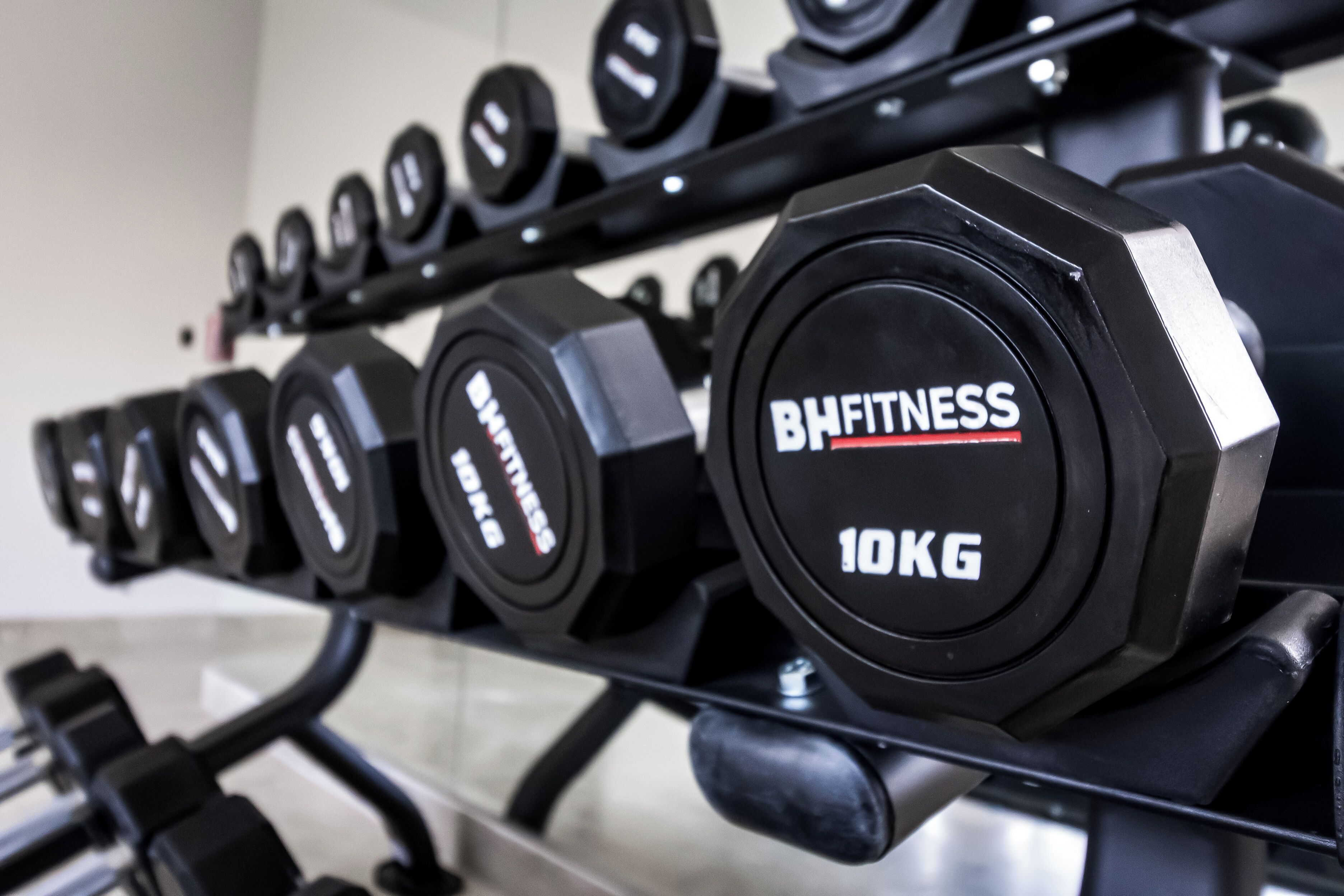 A rack of dumbbells with labels indicating weights, including a 10 kg dumbbell.