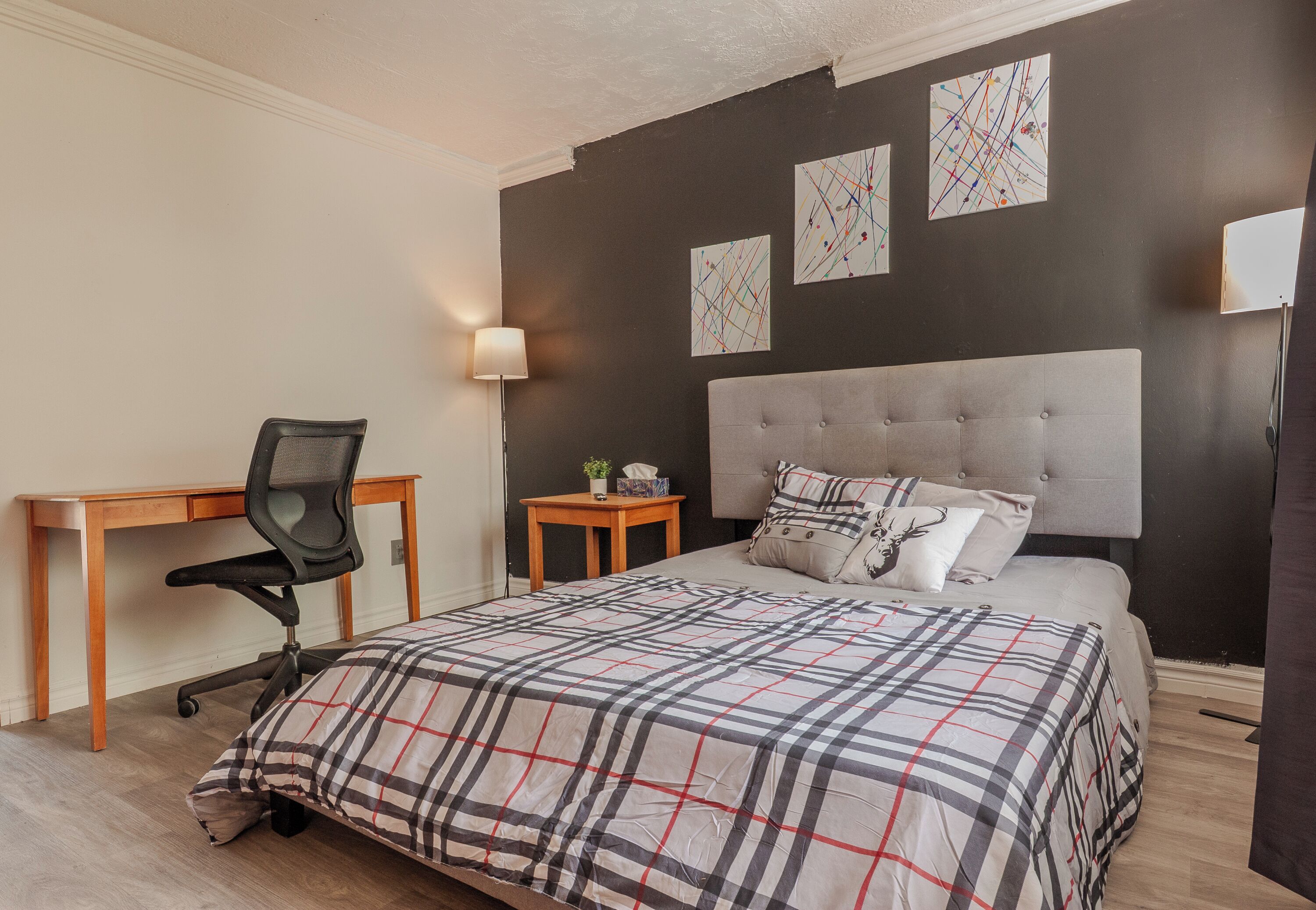A bedroom with a bed, a desk, and a chair.