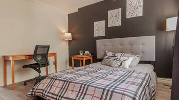 A bedroom with a bed, a desk, and a chair.
