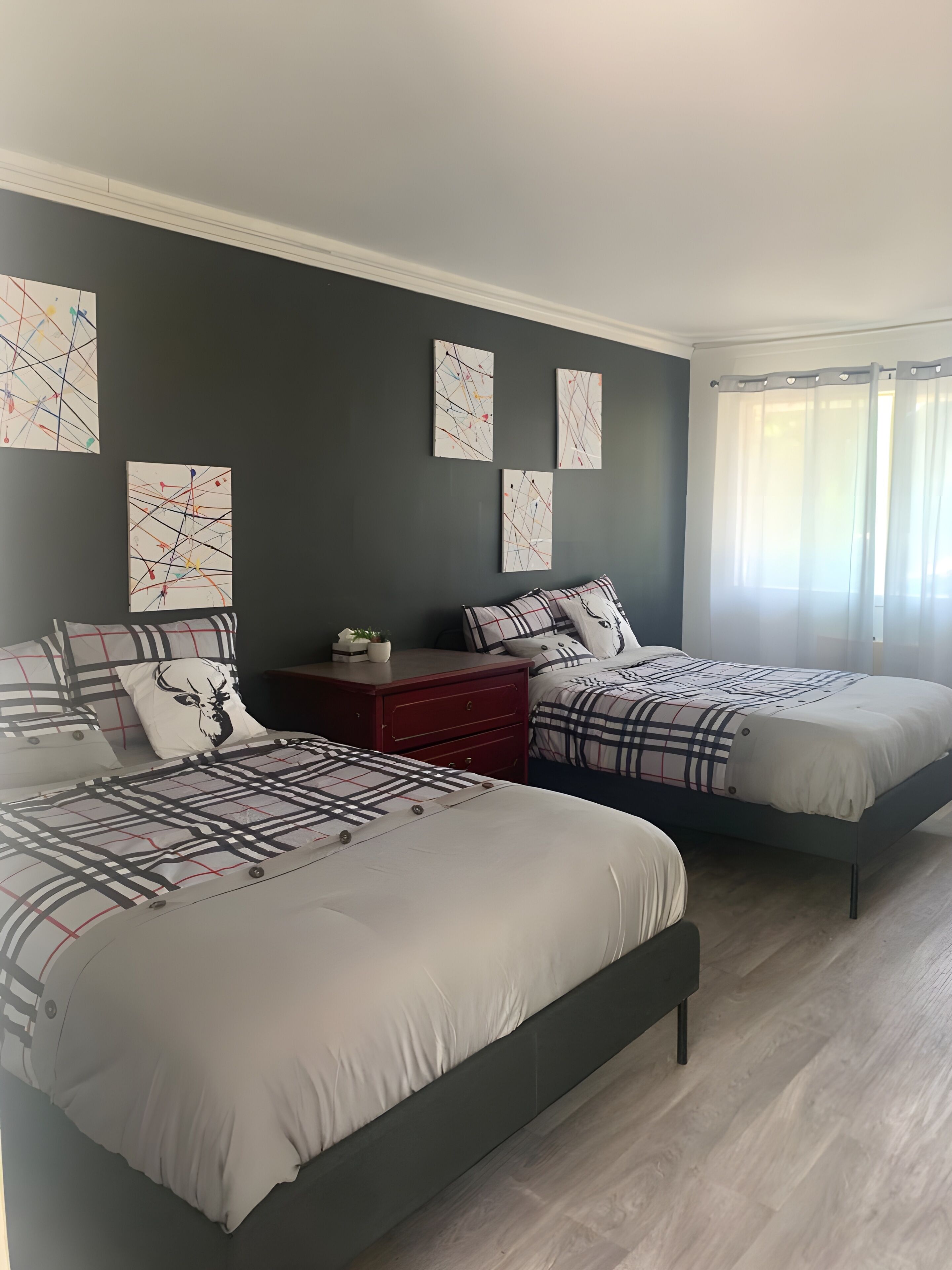 A bedroom with two beds, a nightstand, and artwork on the wall.