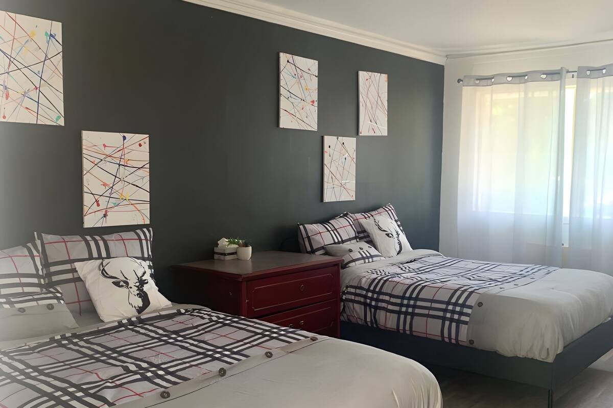 A bedroom with two beds, a nightstand, and artwork on the wall.
