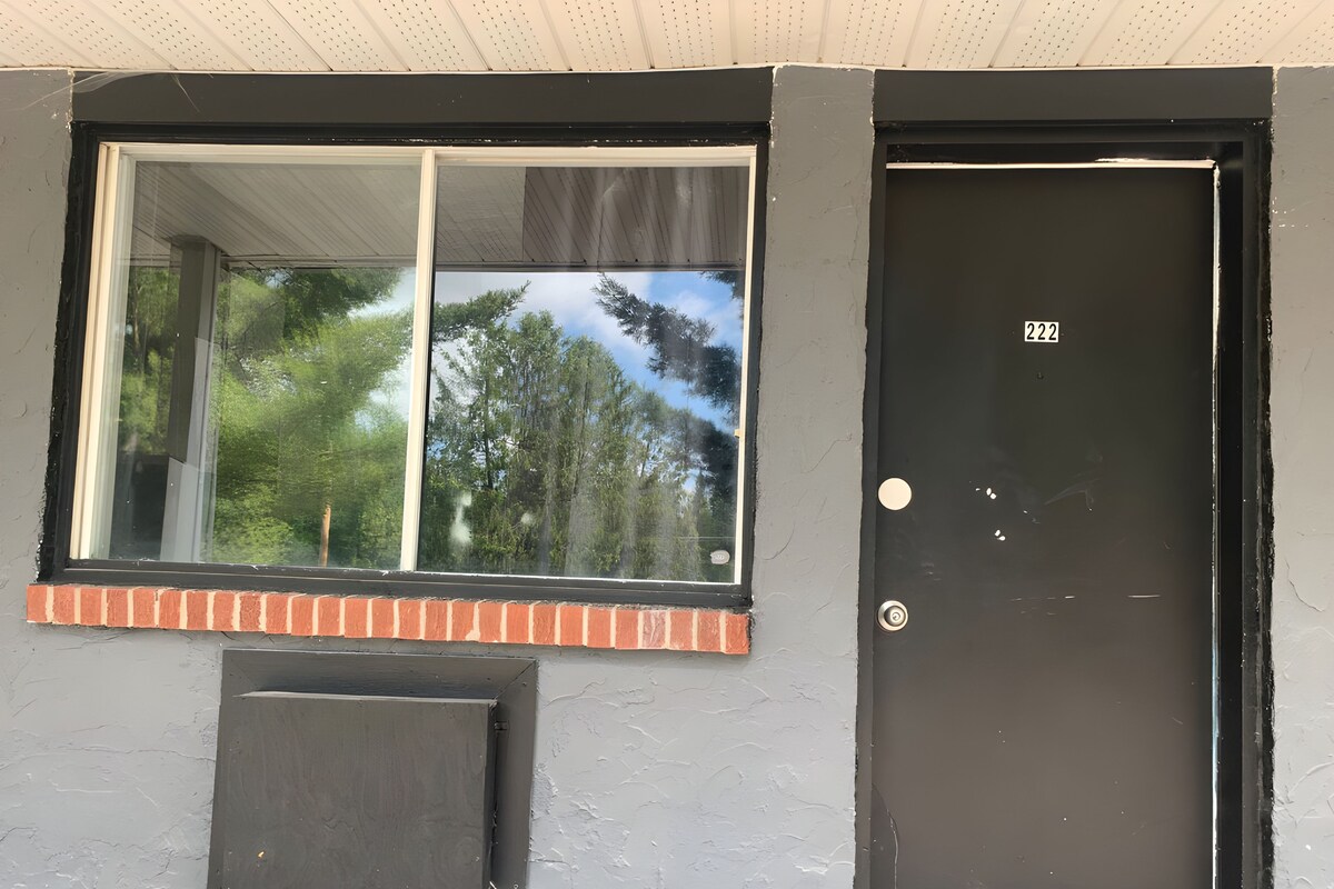 A black door with a number '222' and a window with a brick ledge.