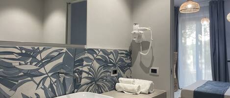 A modern bathroom with a large mirror, a white sink, and a hairdryer mounted on the wall.